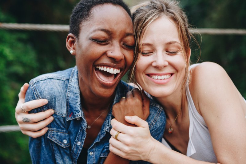 Patient smiling with friend after getting dental implants