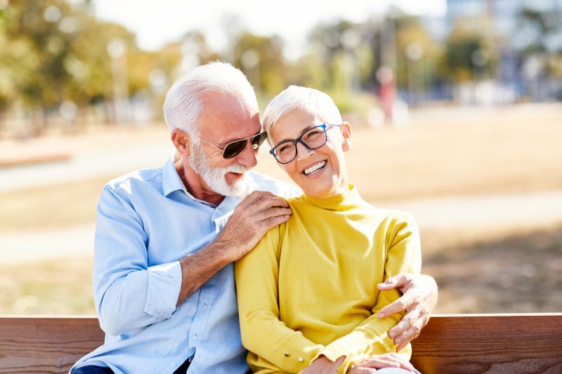 Senior couple smiling together on bench outside