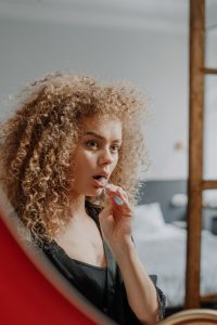 Young woman looking in mirror and brushing her teeth